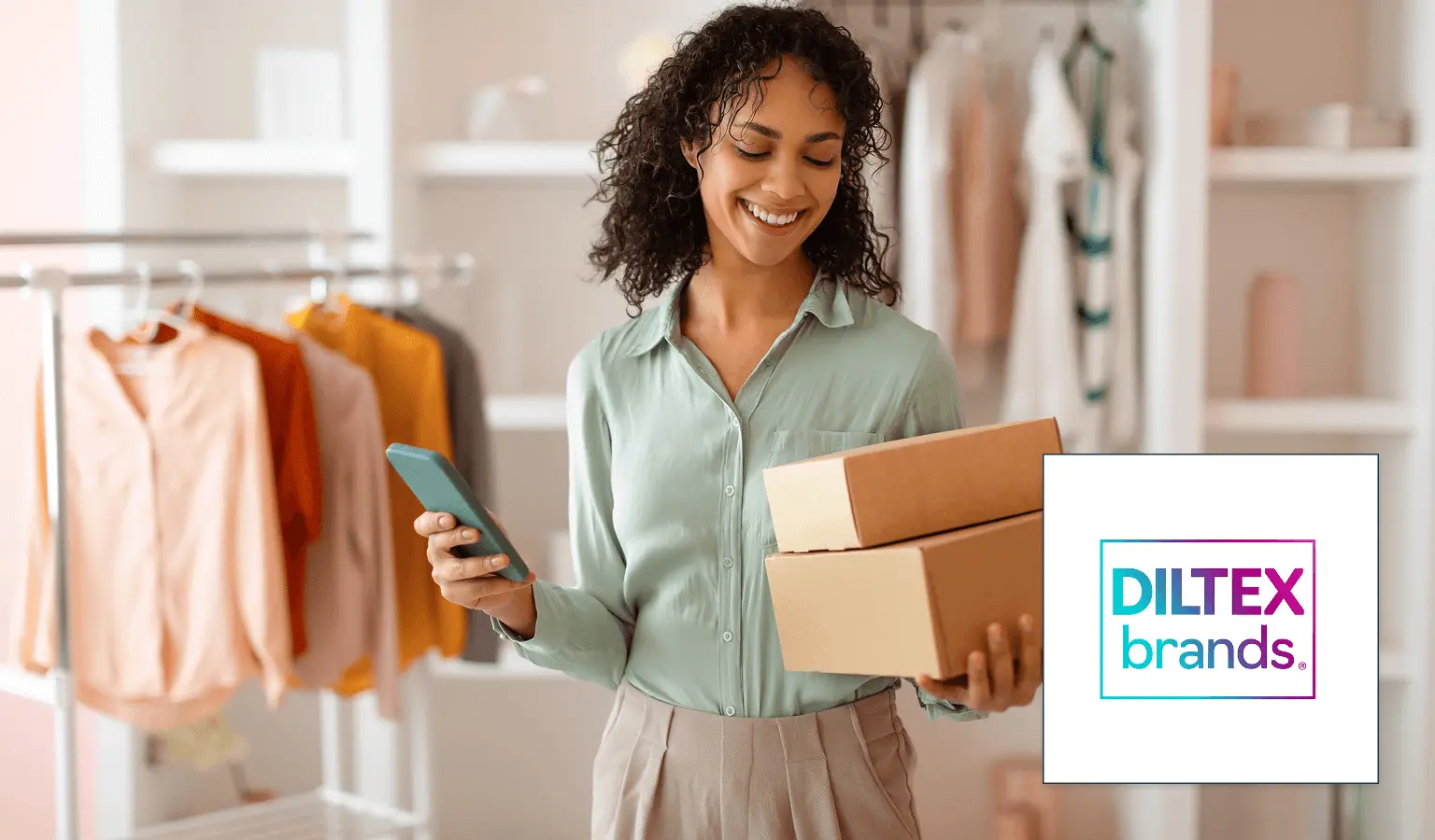 A smiling woman with boxes and a phone in a clothing store.